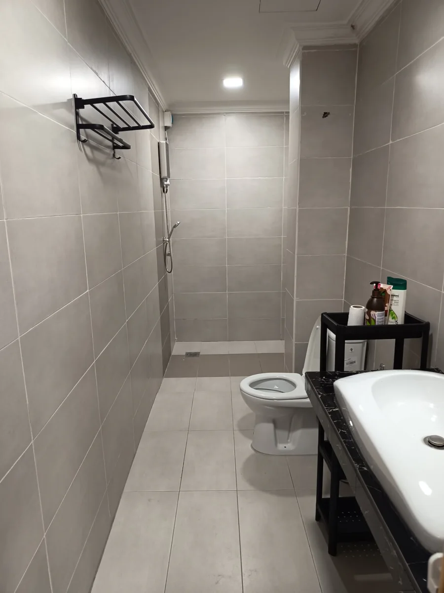 Full view of a tiled bathroom with shower, toilet, washbasin and toiletries