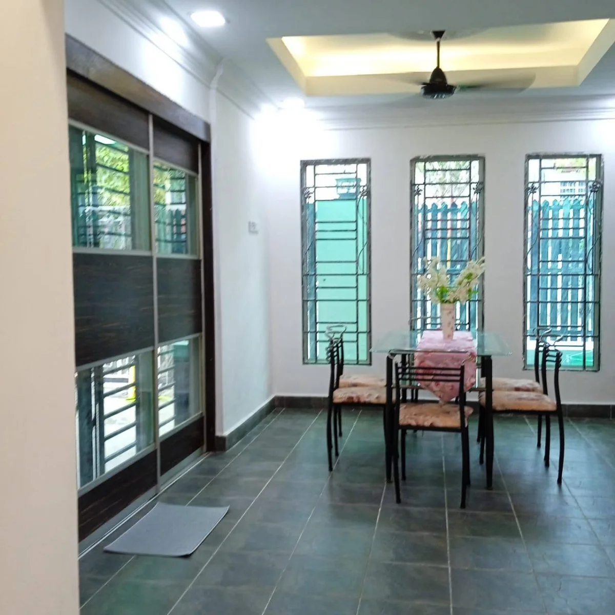 Dining table and chairs beside tall windows at Paradise Lodge
