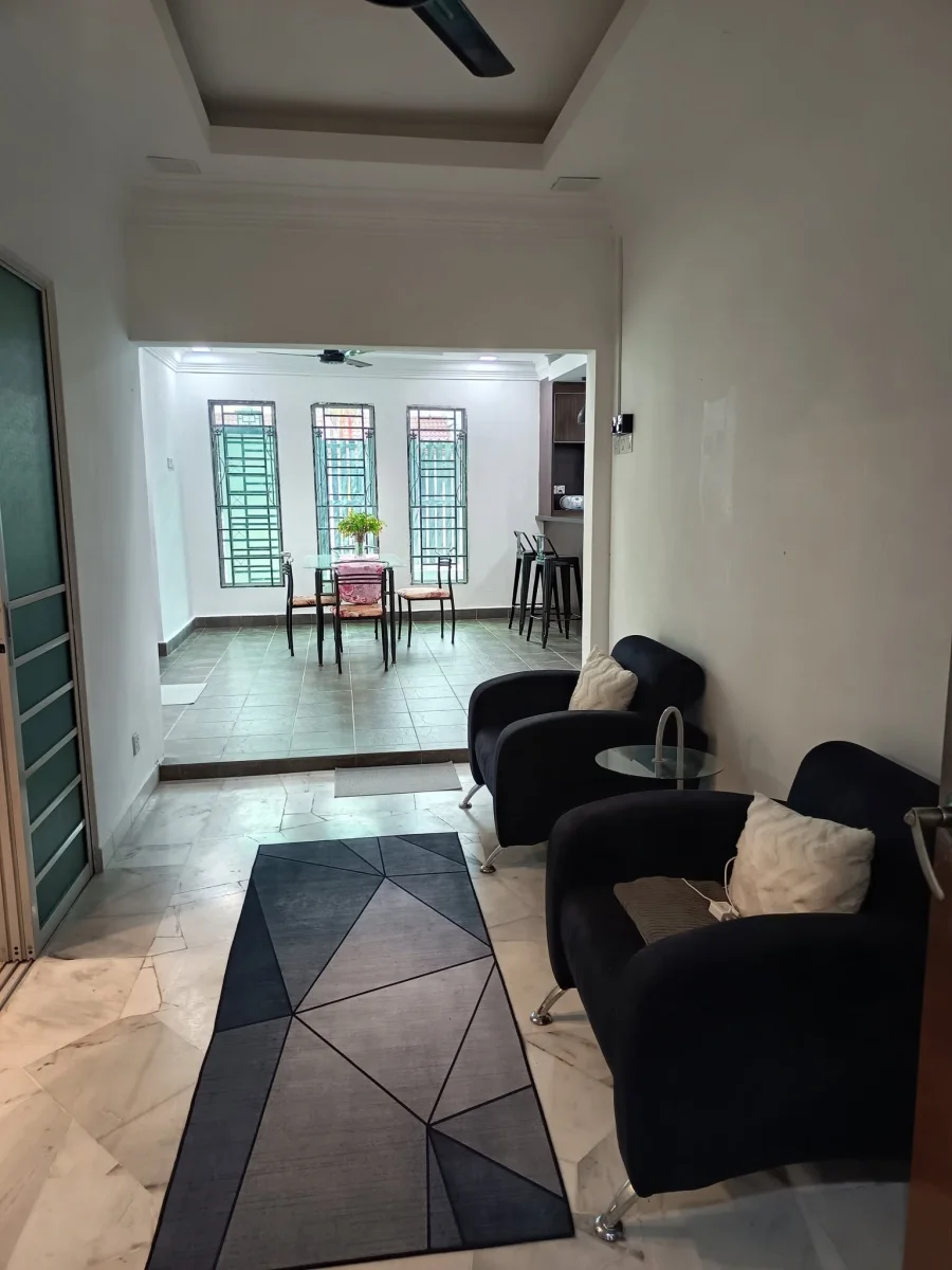 Two dark armchairs in a hallway sitting corner leading towards the dining area