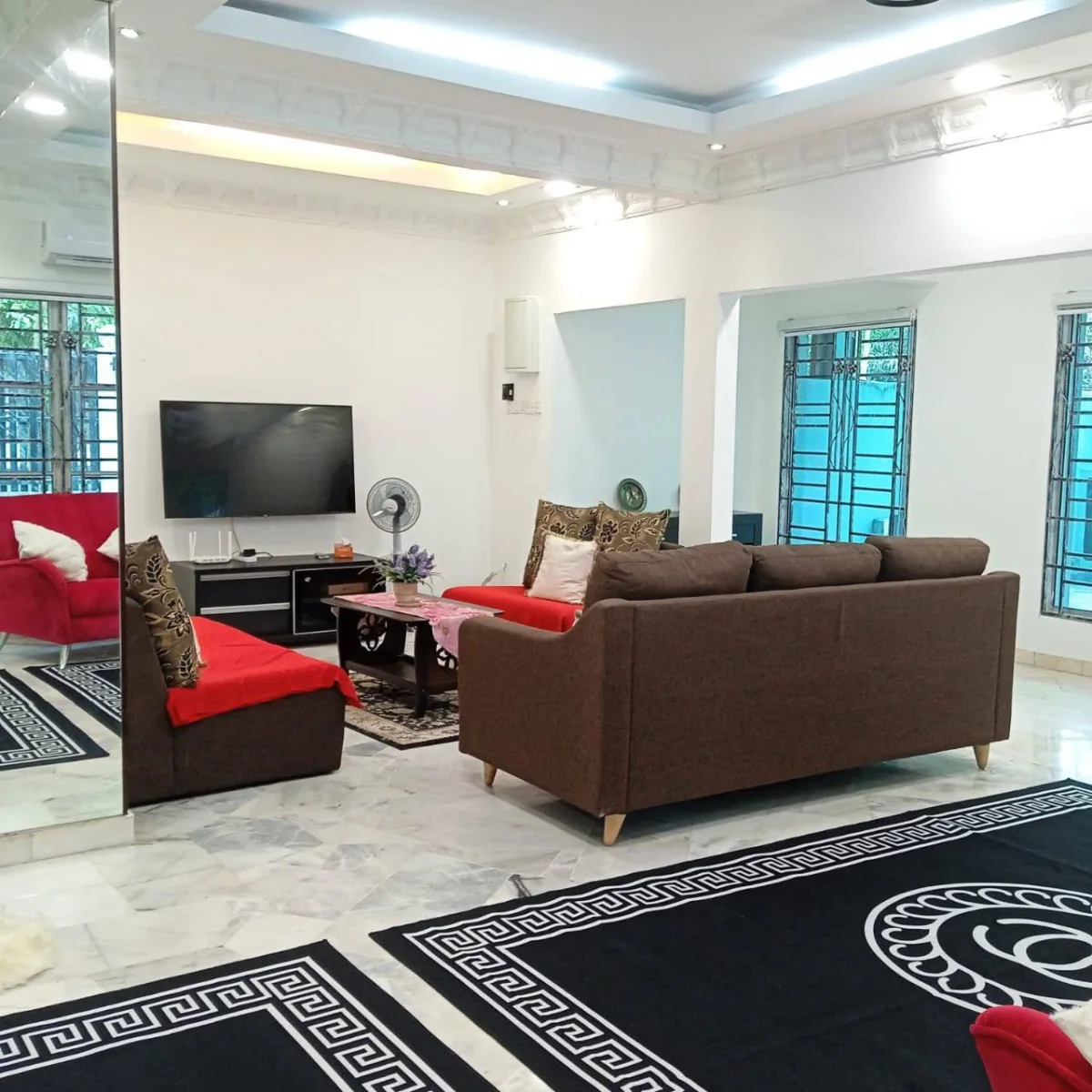Television, sofas and red armchairs in the main living room at Paradise Lodge