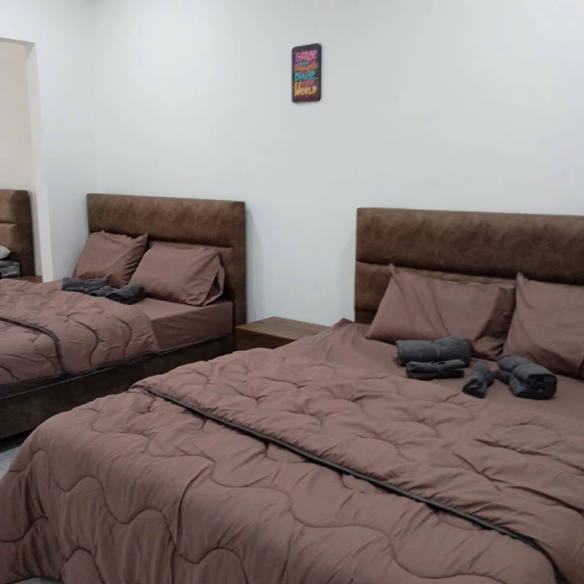 Two beds with a small bedside table between them at Paradise Lodge