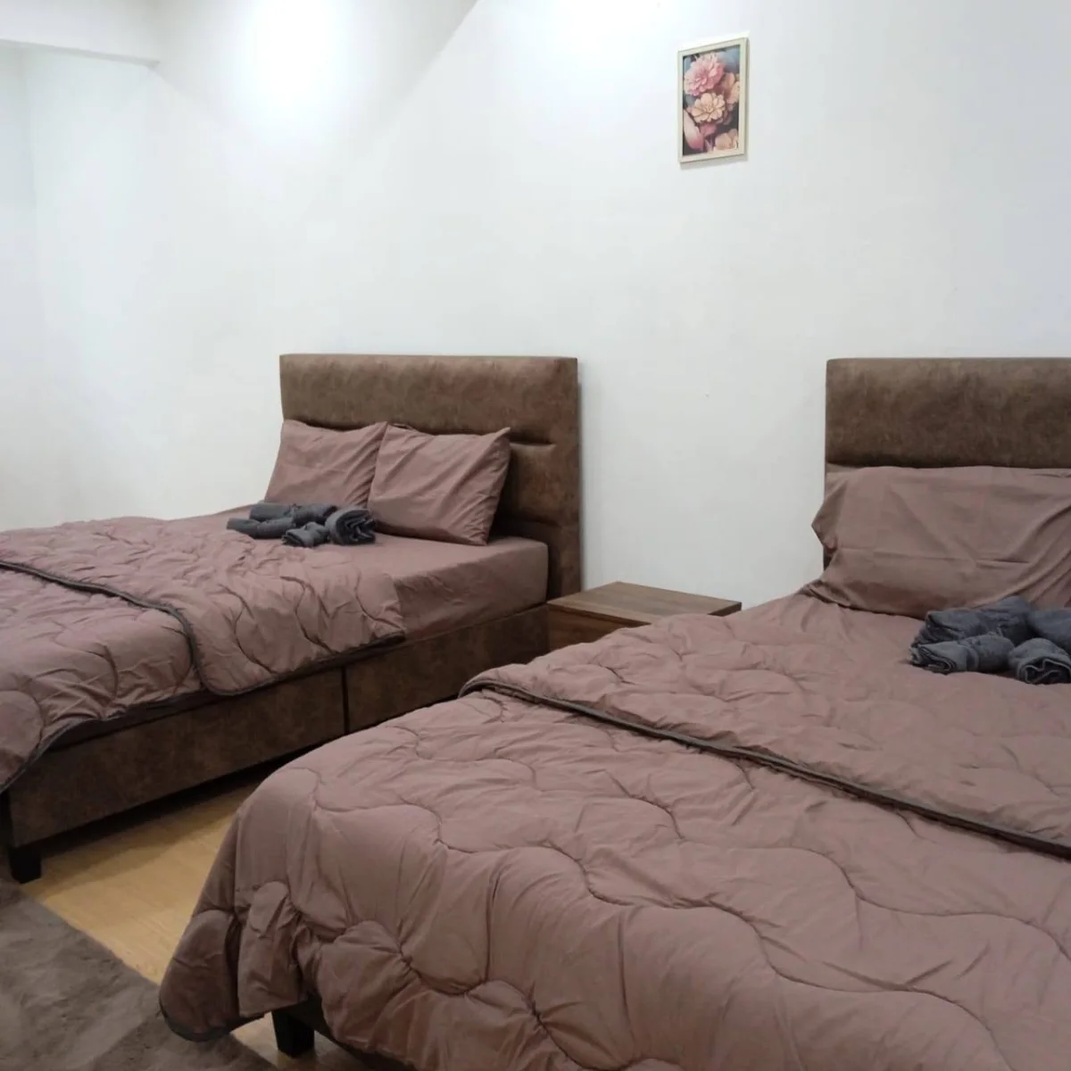 Two neatly made beds with brown bedding in a shared bedroom at Paradise Lodge