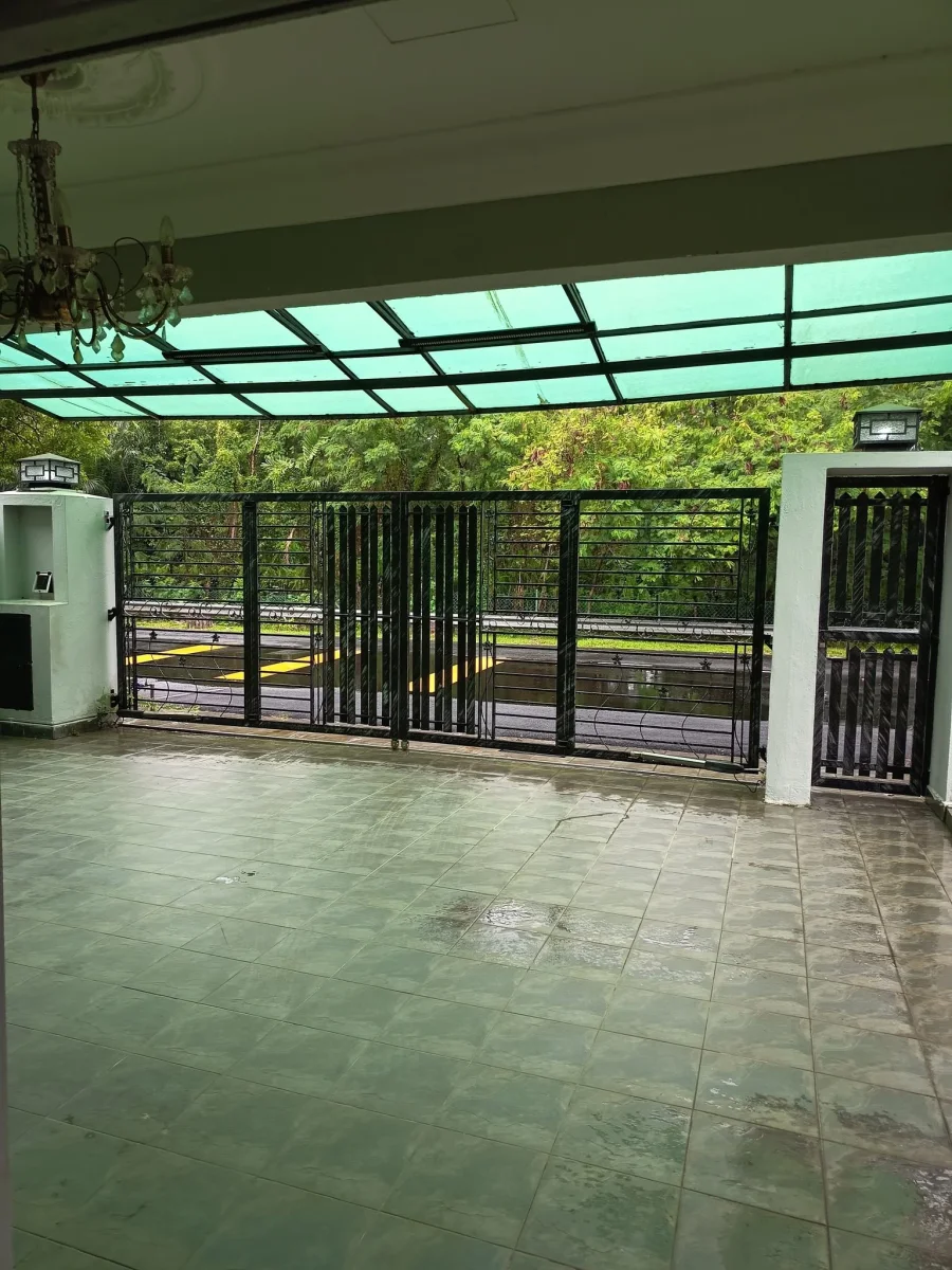 Sheltered front entrance beneath a green canopy facing the gate at Paradise Lodge